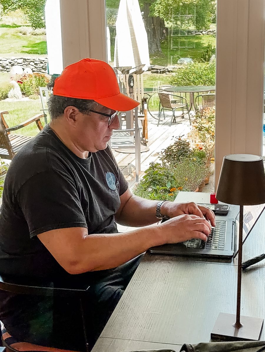 Coachiatry founder working on a laptop at a table by an open porch