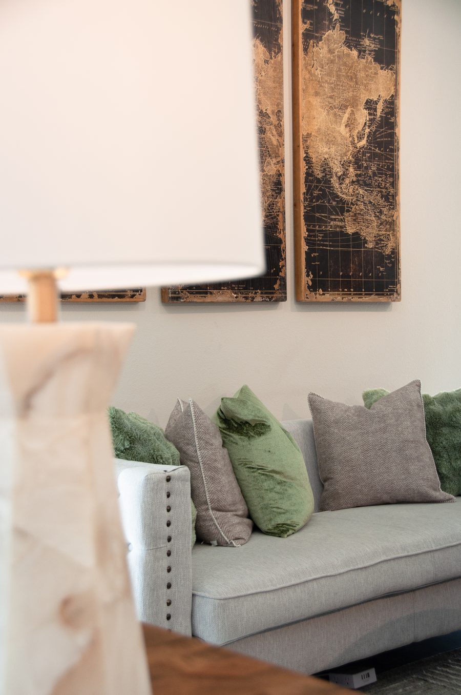 A warm, calm consult room with a soft couch and vintage map artwork